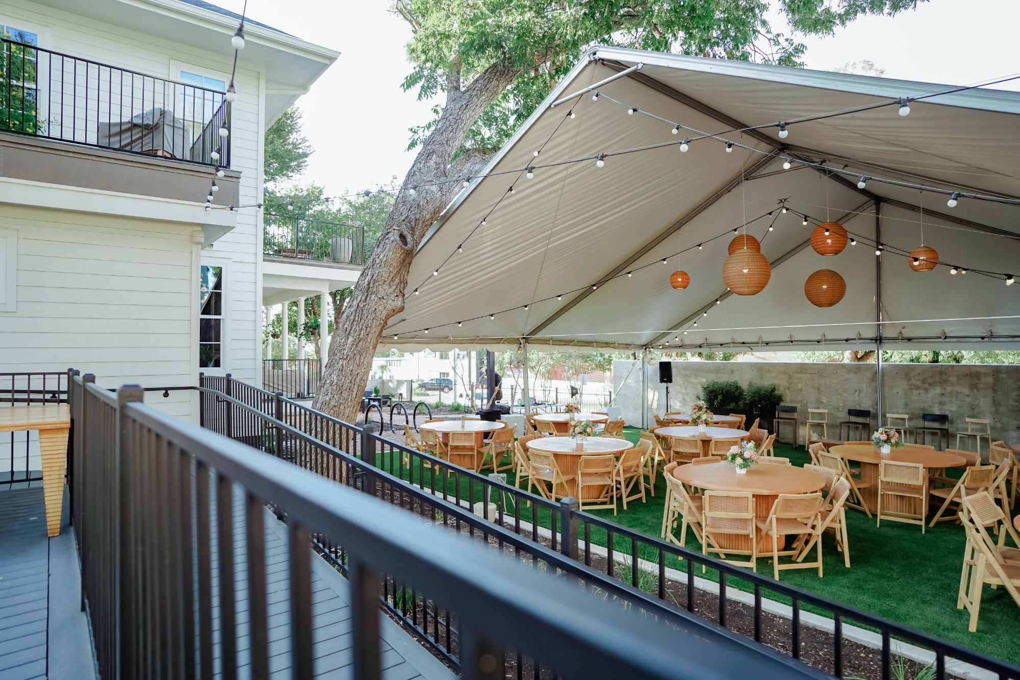 Round tables set beneath the event tent on the lawn at Arena Commons